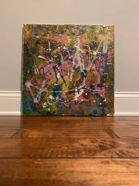 Sold original by Agata May'kowska — Abstract expressionist painting with splashes of pink, green, white, blue, black, and gold, leaning against a beige wall on a wooden floor.