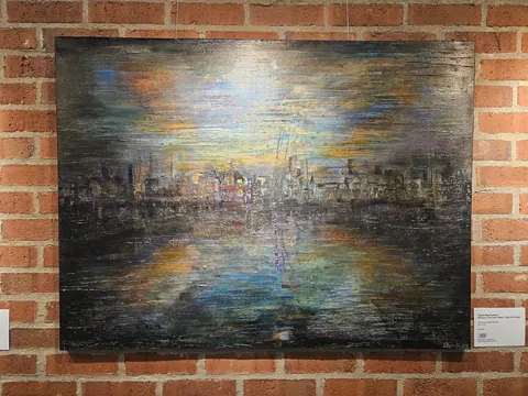Sold original by Agata May'kowska — An abstract painting depicting a city skyline at sunset with vibrant colors and textured brushstrokes, mounted on a brick wall.