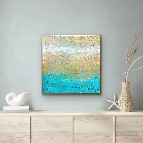 Sold original by Agata May'kowska — Decorative abstract painting with blue, beige, white, and gold textured strokes hanging on a light gray wall above a light wood sideboard with nautical and beach-themed…